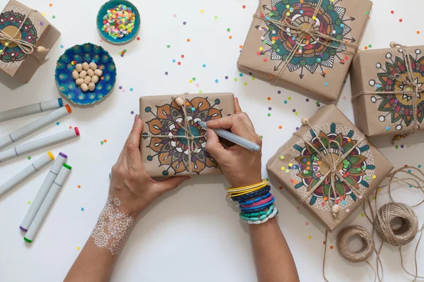 Gifts wrapped in kraft paper. On boxes painted mandala pattern.