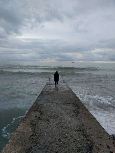 Man stands Alone on pier  in Front of sea