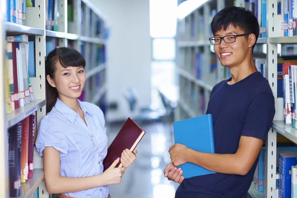 Two young asian college students smile at camera in the libray