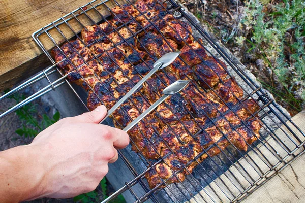 Hand takes just cooked meat from the grill