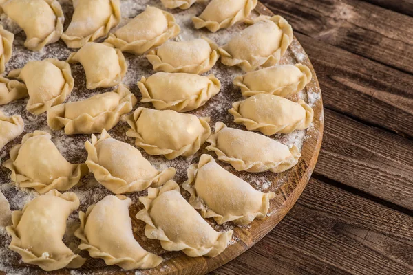 Sculpt pierogy,  cutting board, making  on a  wooden table.