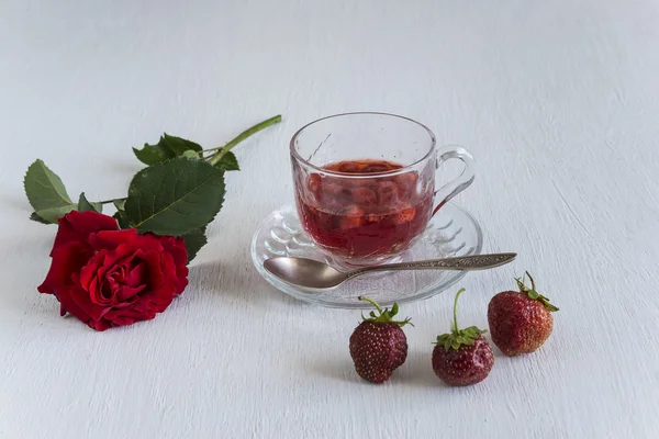 One cup of strawberries jus, one red rose and two strawberries