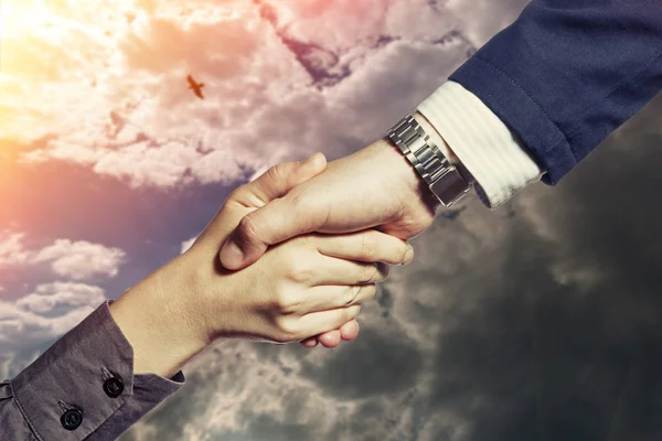 Handshake of two persons, on a sky background