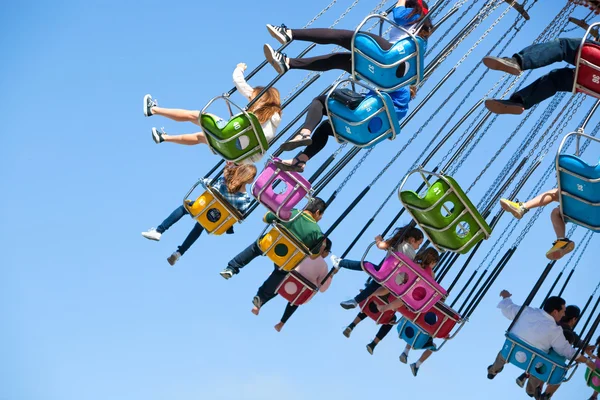 People Enjoying a Swinging Ride on a Sunny Day