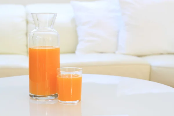 Glass of orange juice on a table in a living room