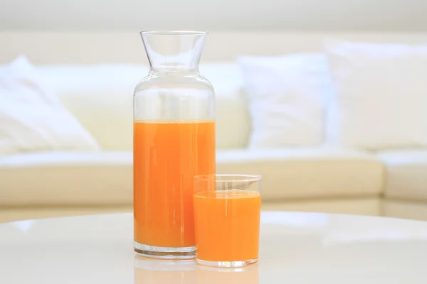 Glass of orange juice on a table in a living room