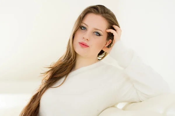 Beautiful young woman in a white sofa