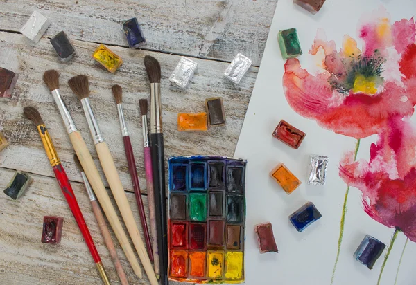 Watercolor paint, brush, painted flowers.