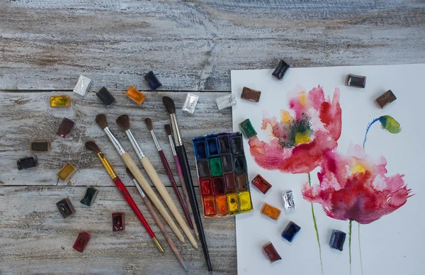 Watercolor paint, brush, painted flowers.