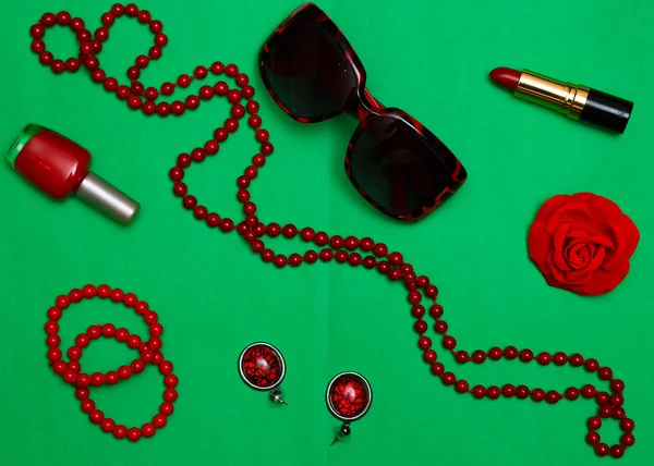 Fashion women set of red accessories on a green background flat lay top view