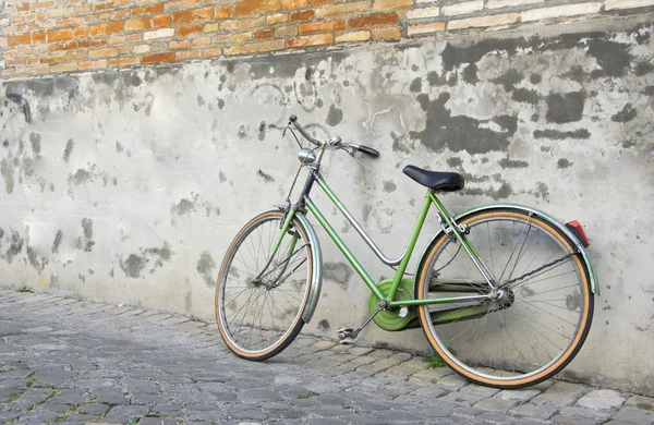 Old retro green bicycle leaning against a wall