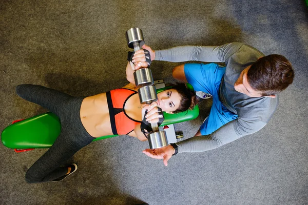 Fitness girl at the gym with free weights and trainer