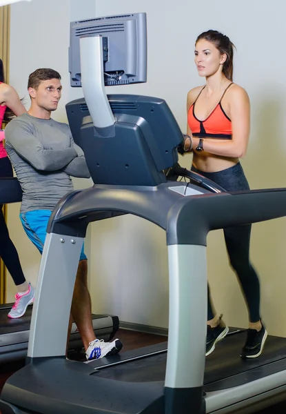 Fitness girl on the treadmill with a trainer