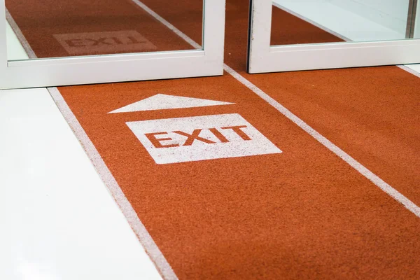 White exit sign arrow painted on the carpet - airport / transportation sign