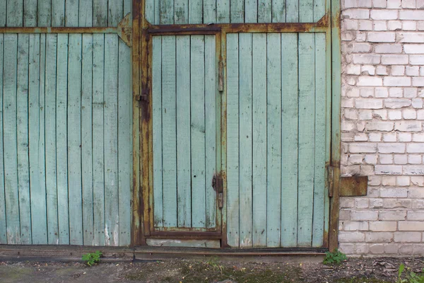 The gate and the door of the green board in rusty metal frame