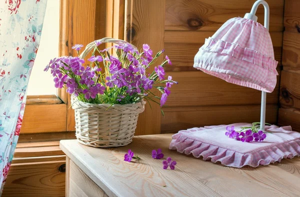 Pink phlox in basket near the lamp in cottage interior