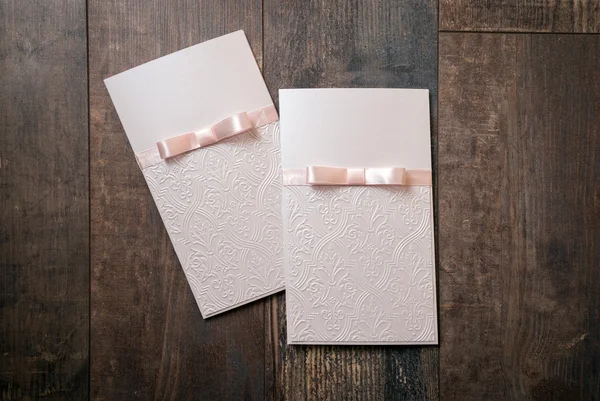 Handmade card with embossed details and pink bow on wood background