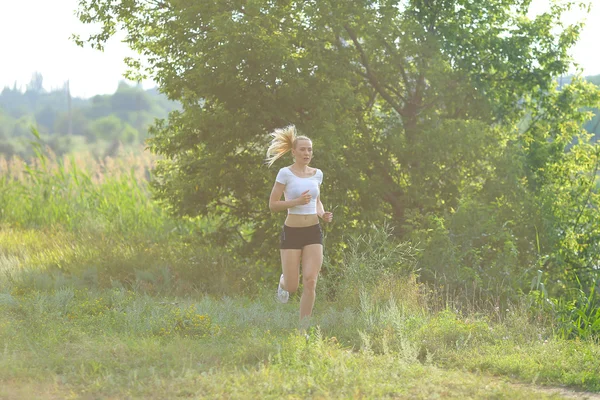 Young beautiful woman running shows press stomach workout training wearing top.