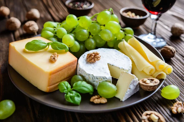 Assorted cheese plate with fruit, walnuts and red vine