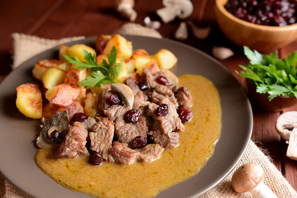 Wild boar meat with roasted potatoes, mushrooms and cranberries