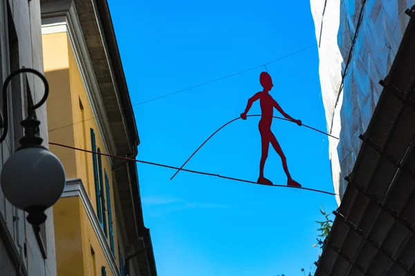 Novara, Italy - October 18, 2016: Installing modern silhouette equilibrist against the sky tightrope walker located between the houses.