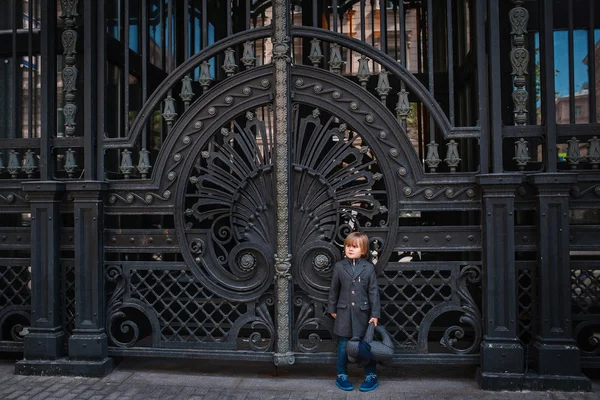 Little boy by forged gates