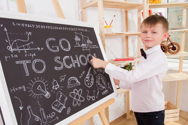 Boy during a lesson is at the blackboard and shows her pointer