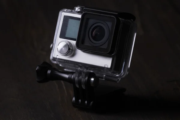 Action camera in a protective box on dark wooden background