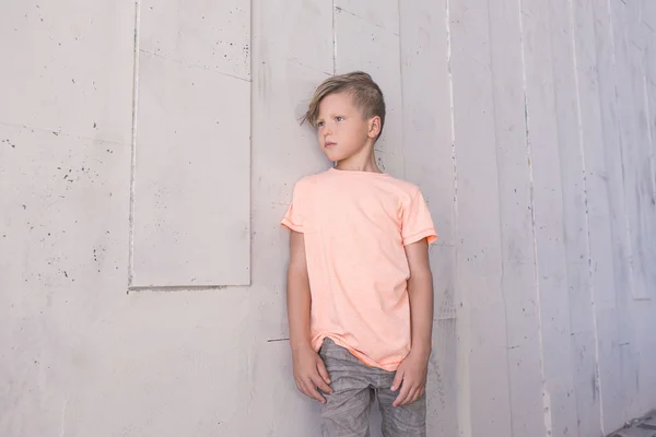Stylish boy leaned on the wall and looking to the side . He\'s go