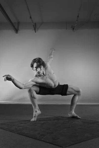 Young stong man dancing in the studio. Flexible body.Black and white.Full length.