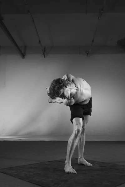 Young stong man dancing in the studio. Flexible body. Black and white.