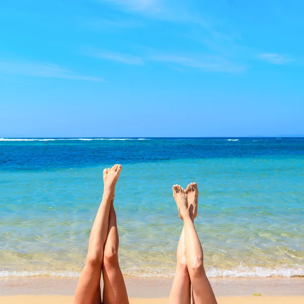 Women\'s legs up with tropical  beach background.