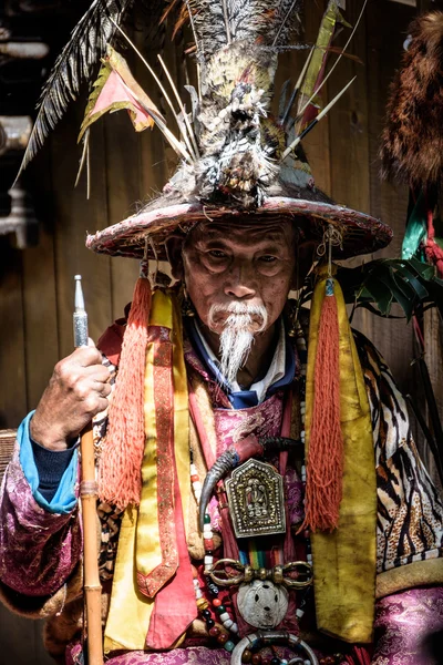 Old man wearing traditional Chinese dresses to show tourists in Lijiang old town.