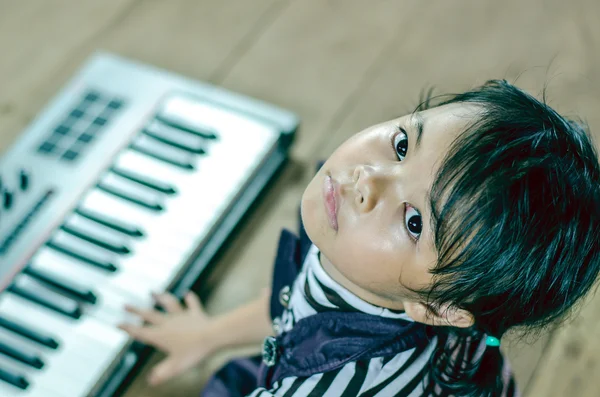 Little girl asia playing piano sitting on the floor