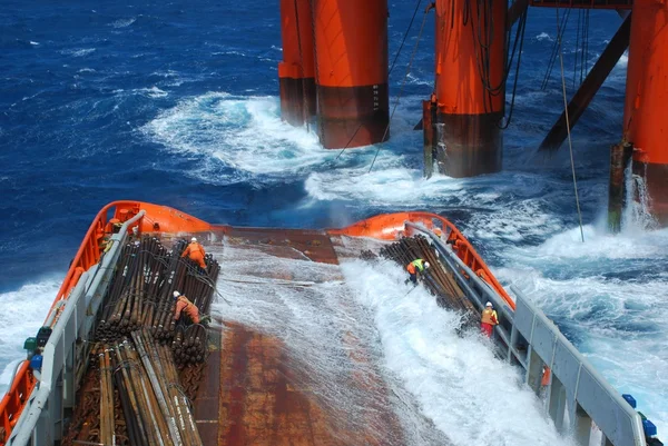Big wave during unloading under semi submersible oil rig near South Africa. pipes on deck. real seaman job, danger, rough weather