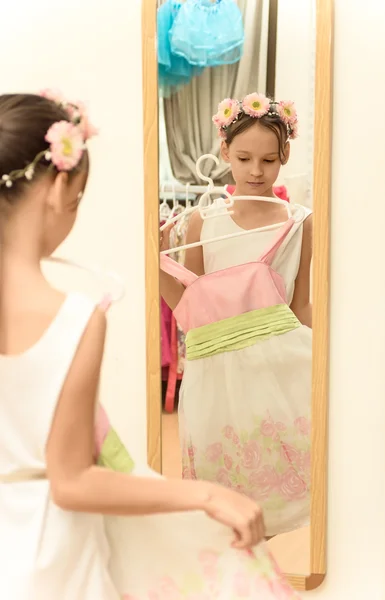 Little girl looking in mirror with new dress in hands