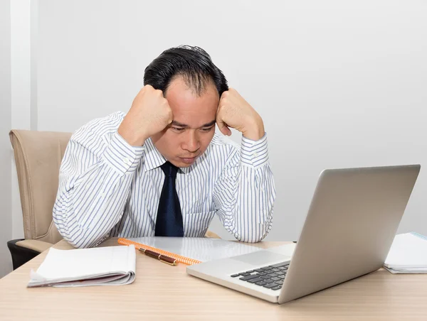 Worried asian businessman looking at laptop with hands on head