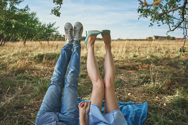 Legs of a couple lying on the grass in the apple orchard