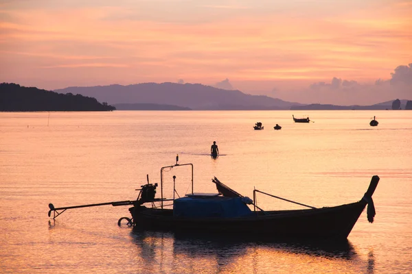 Sunset scene with orange shade of the sky with boat floating on the sea.