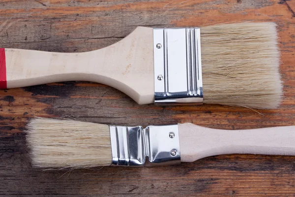 Pair of new paint brush on old wooden board construction concept