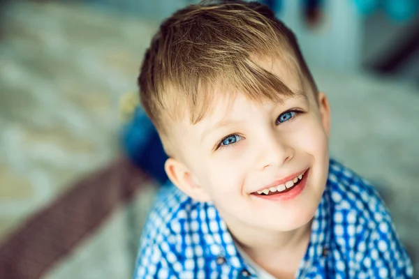 Portrait of a blue-eyed smiling little boy lying on his parents\'  bed.