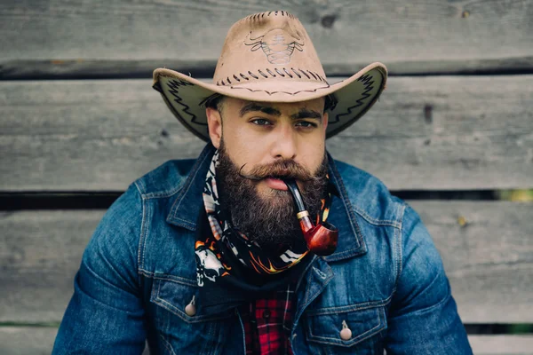 Bearded cowboy with smoking pipe