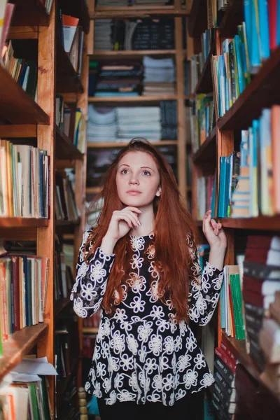 Young redhead girl in library