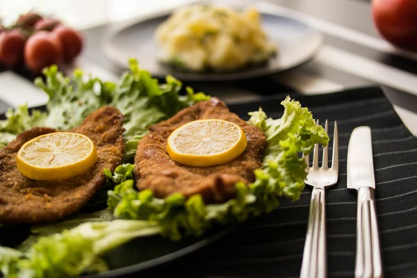Schnitzel serve with greens and lemon