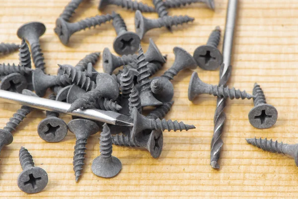 Black screws and tools on wood