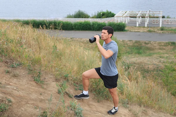 A young man walking on the trail. travel sport lifestyle concept. Young athlete drinking fresh water.