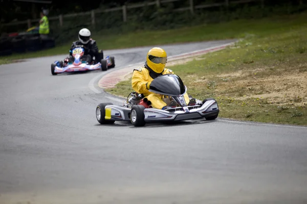 Two racing go karts zooming along at full pace on the race circuit