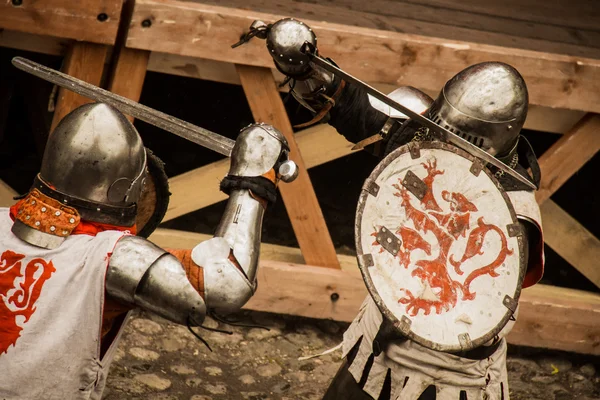Medieval warriors in iron armor fighting with swords