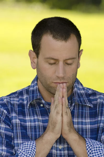 Young man praying outdoors.