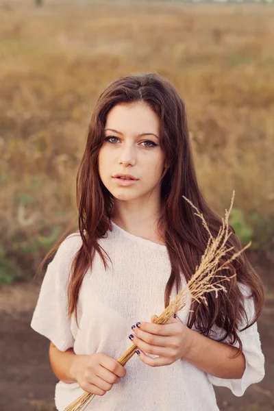 Young girl with long brown hair holds a bundle of ears